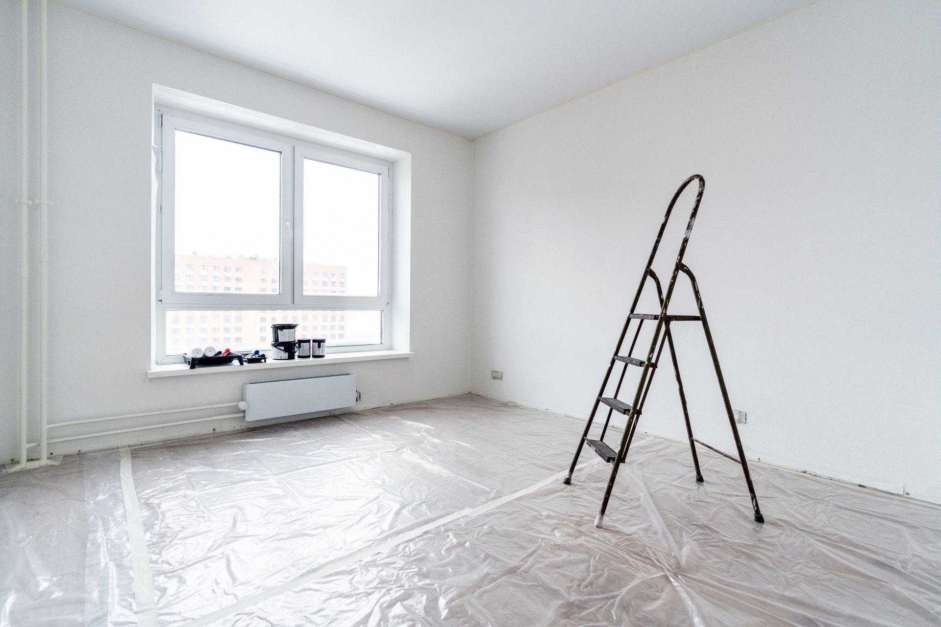 An empty room prepared for painting, the floor is covered with polythene